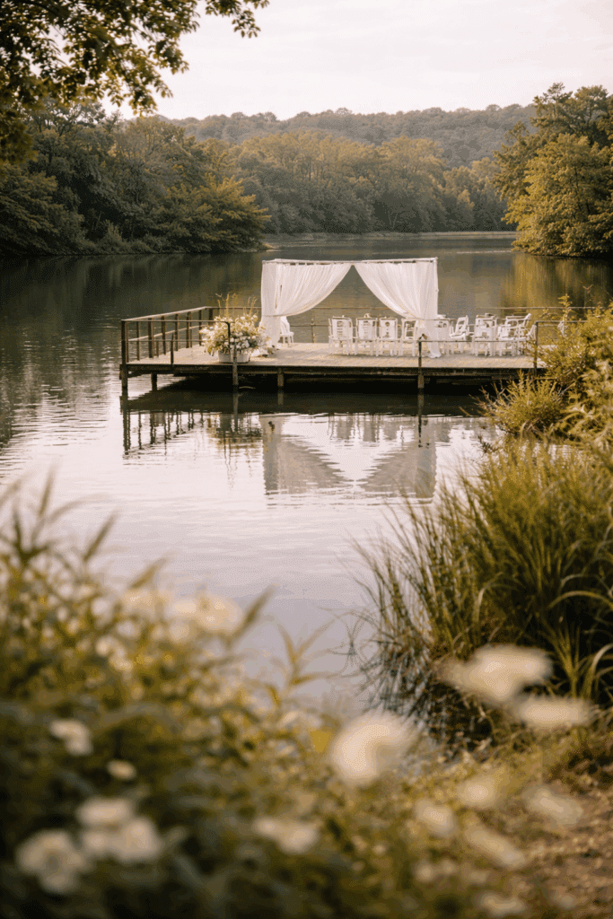 Mariage romantique sur ponton : Cérémonie au bord du lac. Cérémonie de mariage intime sur un ponton en bois au milieu d'un lac forestier. Arche de mousseline blanche et chaises élégantes.