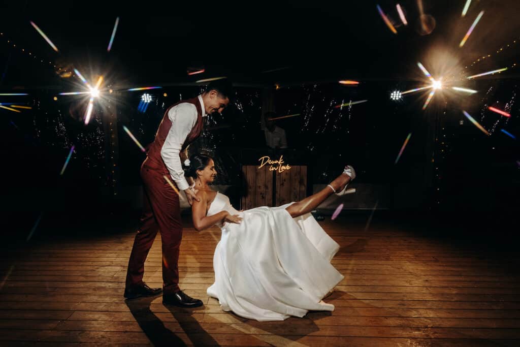 Mariage : Danse folle "Drunk in Love" des mariés. Les mariés joyeux font une figure de danse lors de leur soirée. Éclairage festif et enseigne néon "Drunk in love" en arrière-plan.